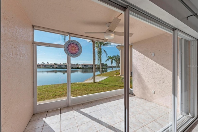 doorway with light tile patterned floors, a wall of windows, ceiling fan, a water view, and a textured ceiling