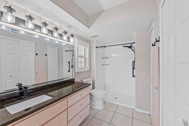 bathroom featuring tile patterned floors, toilet, vanity, and a shower