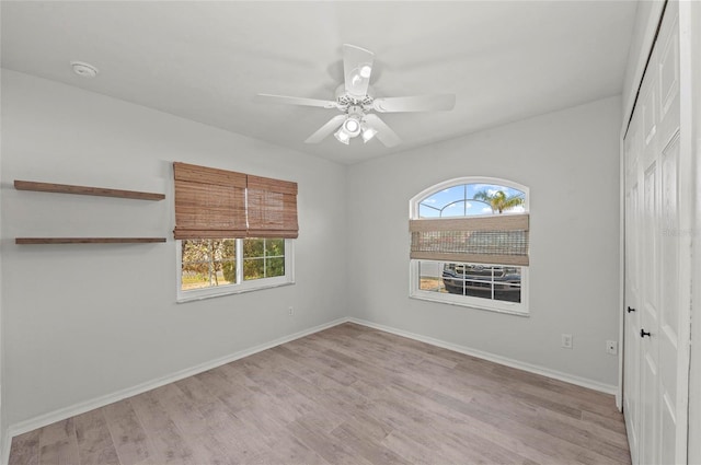 spare room featuring a healthy amount of sunlight, ceiling fan, and light hardwood / wood-style flooring