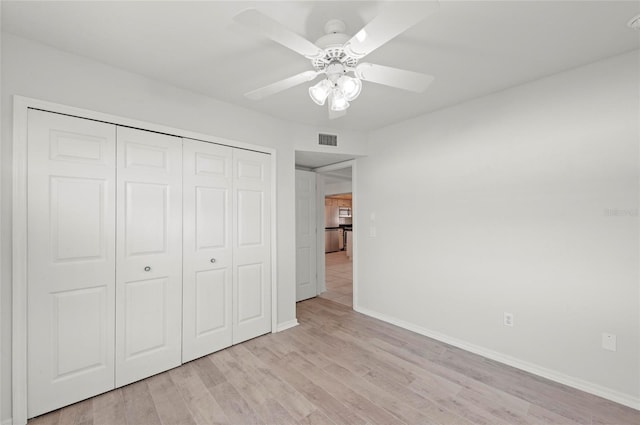 unfurnished bedroom with ceiling fan, light wood-type flooring, and a closet