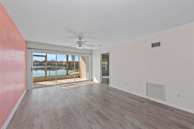 empty room with a water view, ceiling fan, and hardwood / wood-style flooring