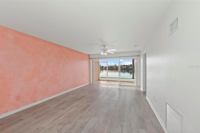 spare room featuring a water view, ceiling fan, and light wood-type flooring