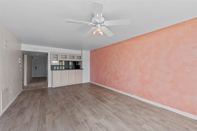 unfurnished living room featuring ceiling fan and light hardwood / wood-style floors