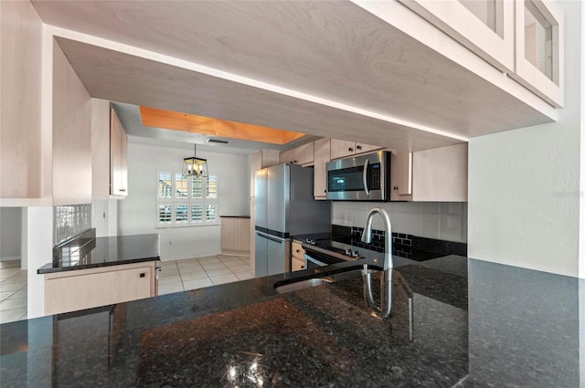 kitchen with tasteful backsplash, dark stone countertops, hanging light fixtures, light tile patterned floors, and stainless steel appliances