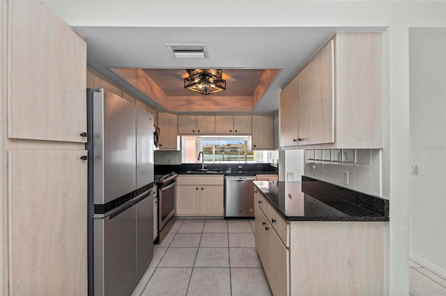 kitchen featuring a raised ceiling, appliances with stainless steel finishes, sink, and light brown cabinetry