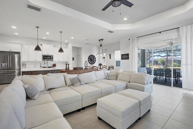 tiled living room featuring a raised ceiling and ceiling fan