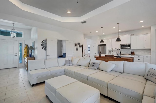 living room featuring light tile patterned flooring, a raised ceiling, and a high ceiling