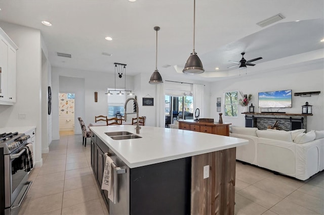 kitchen with sink, appliances with stainless steel finishes, a kitchen island with sink, white cabinetry, and hanging light fixtures