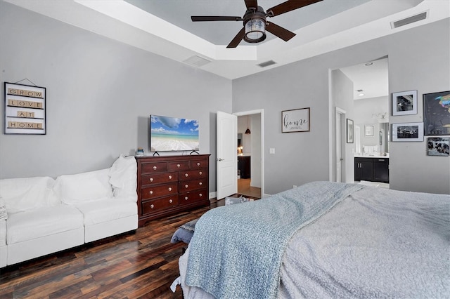 bedroom with ceiling fan, ensuite bath, dark hardwood / wood-style flooring, and a raised ceiling