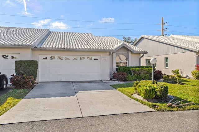 view of front of home with concrete driveway, an attached garage, a tile roof, and stucco siding