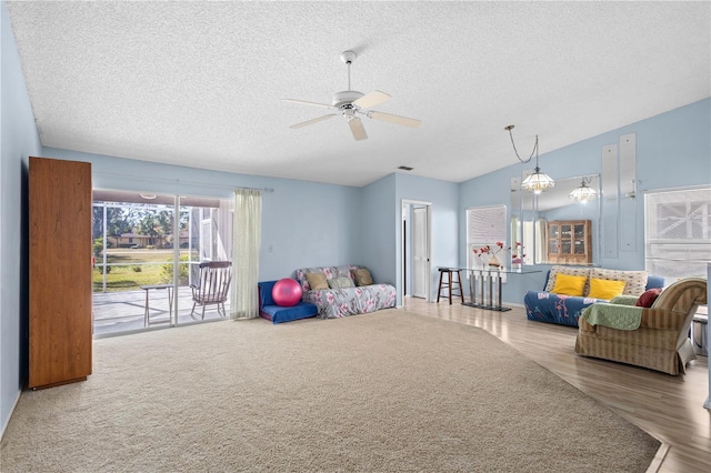 living room with wood-type flooring, a textured ceiling, vaulted ceiling, and ceiling fan