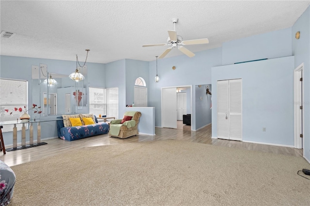 carpeted living room with ceiling fan, high vaulted ceiling, and a textured ceiling