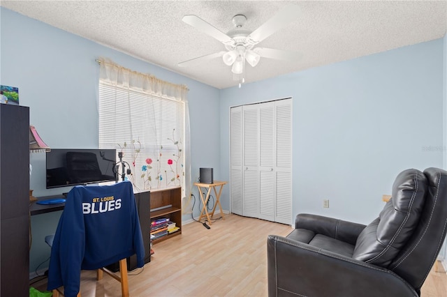 home office with a textured ceiling, light hardwood / wood-style floors, and ceiling fan