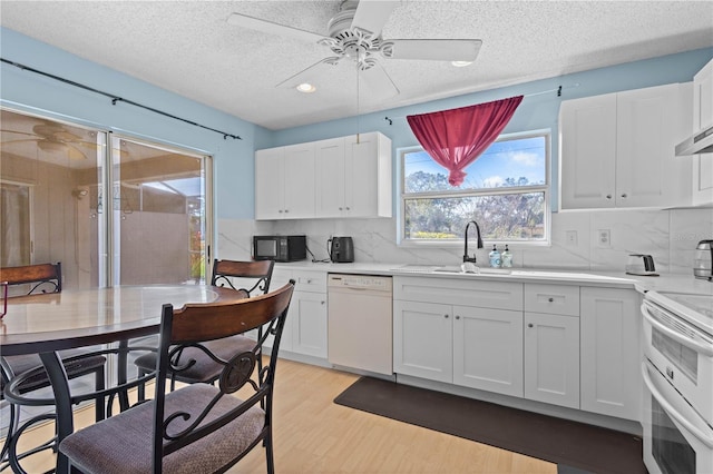 kitchen with white appliances, sink, light hardwood / wood-style flooring, and white cabinets