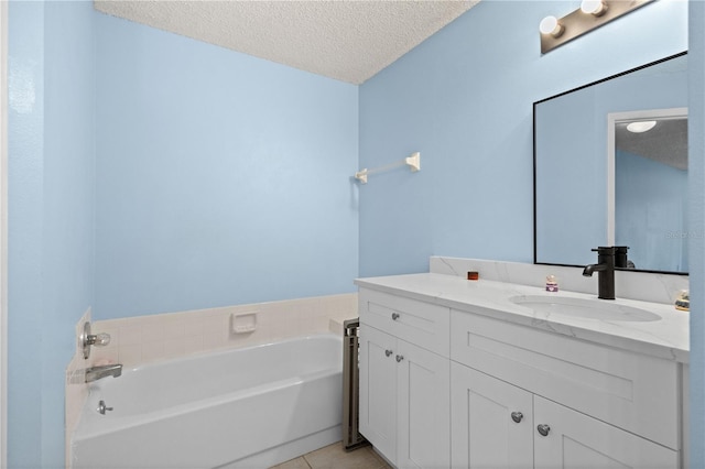 full bathroom with a garden tub, tile patterned floors, a textured ceiling, and vanity