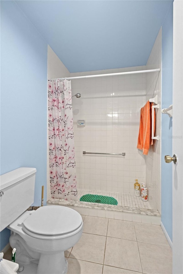 bathroom featuring toilet, a stall shower, and tile patterned floors