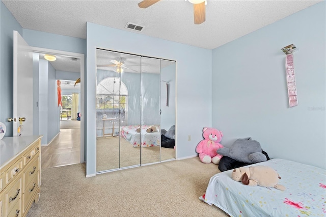 carpeted bedroom with ceiling fan, a textured ceiling, and a closet