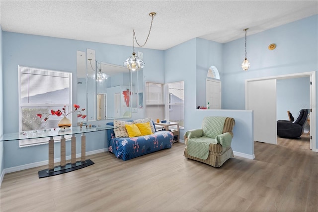 living area with a textured ceiling, baseboards, and wood finished floors