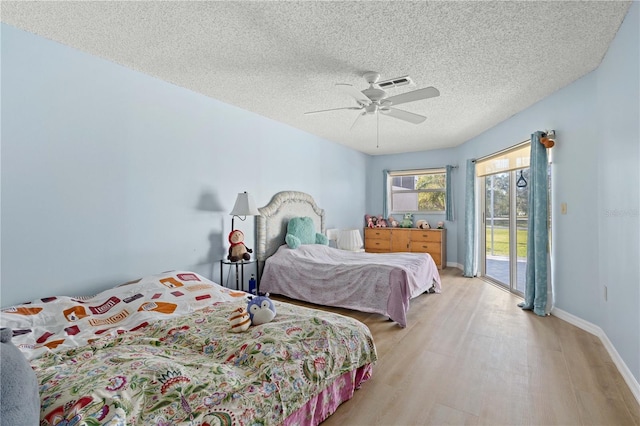 bedroom with a textured ceiling, visible vents, baseboards, light wood-style floors, and access to outside