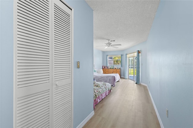 bedroom with baseboards, wood finished floors, access to outside, a textured ceiling, and a closet