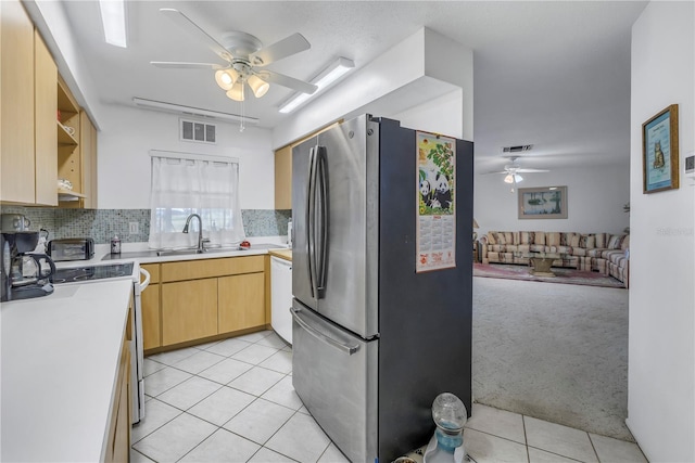 kitchen featuring sink, light tile patterned floors, stainless steel refrigerator, tasteful backsplash, and light brown cabinetry