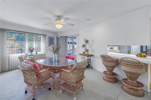 dining space featuring light carpet and ceiling fan