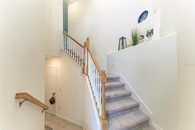 stairway featuring a towering ceiling and tile patterned floors