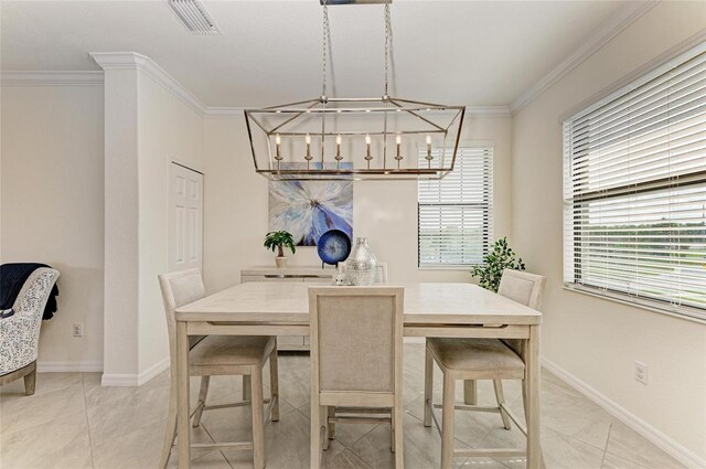 dining area with a notable chandelier, light tile patterned floors, and ornamental molding