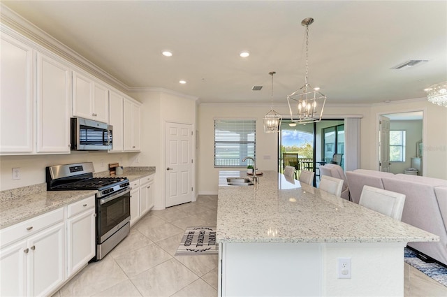 kitchen with appliances with stainless steel finishes, a kitchen island with sink, and white cabinets