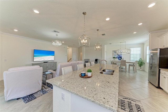 kitchen with white cabinetry, a spacious island, stainless steel fridge, and sink