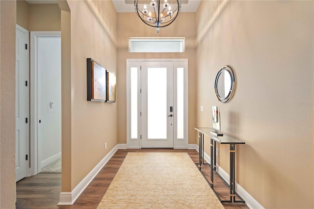 entryway with dark wood-type flooring and a notable chandelier