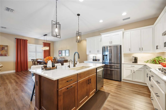 kitchen featuring a breakfast bar, sink, appliances with stainless steel finishes, an island with sink, and white cabinets