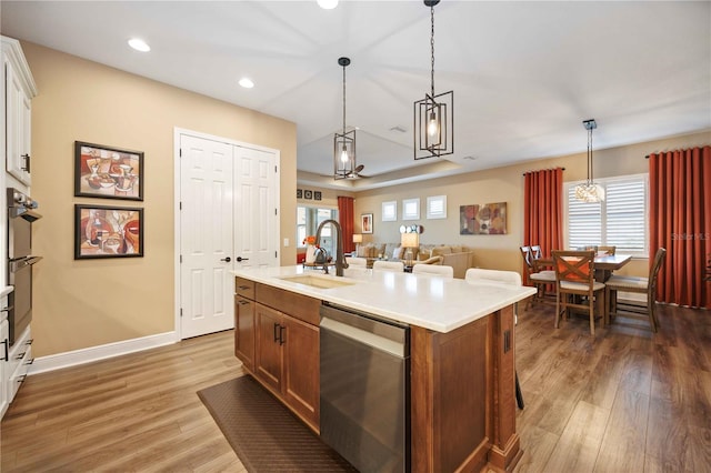 kitchen with appliances with stainless steel finishes, white cabinetry, sink, hanging light fixtures, and a center island with sink