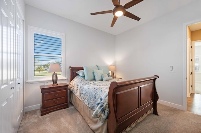 bedroom with ceiling fan, light colored carpet, and a closet