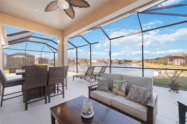 view of patio featuring a lanai, outdoor lounge area, ceiling fan, and a water view