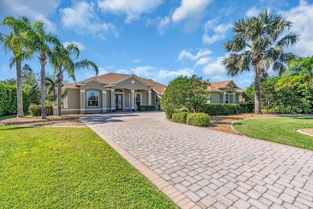 mediterranean / spanish home featuring a front yard, decorative driveway, french doors, and stucco siding