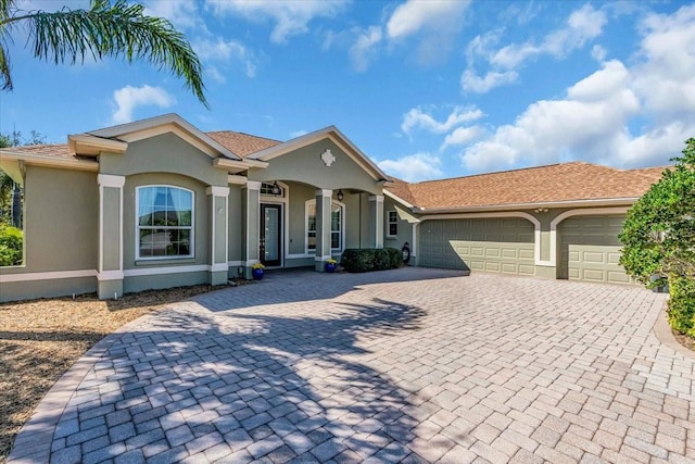 view of front of property with a garage, decorative driveway, and stucco siding