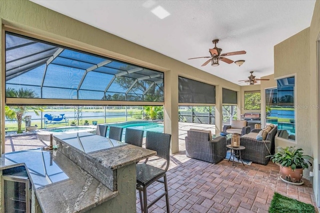 view of patio featuring outdoor dry bar, glass enclosure, a ceiling fan, and an outdoor pool