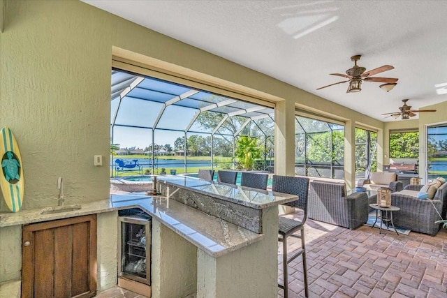 view of patio / terrace featuring outdoor dry bar, glass enclosure, wine cooler, and a sink