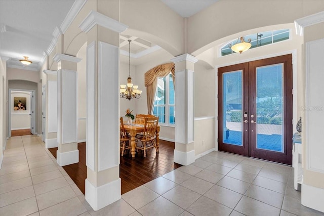 foyer entrance featuring arched walkways, french doors, ornamental molding, ornate columns, and tile patterned floors