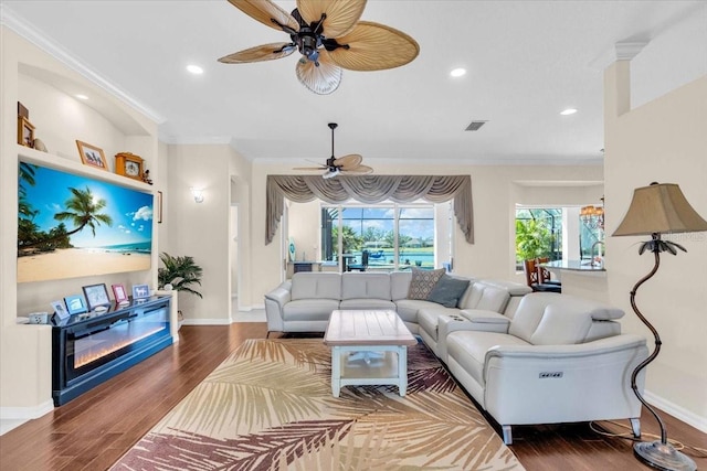 living area with ornamental molding, wood finished floors, visible vents, and recessed lighting