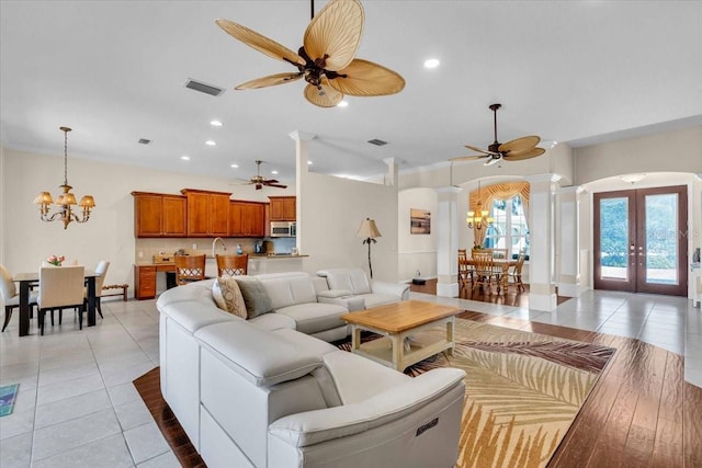 living area featuring arched walkways, light tile patterned floors, recessed lighting, french doors, and ornate columns