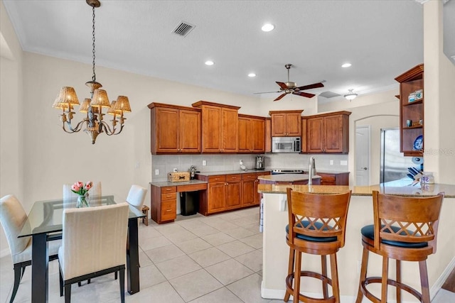 kitchen featuring open shelves, appliances with stainless steel finishes, brown cabinetry, and visible vents