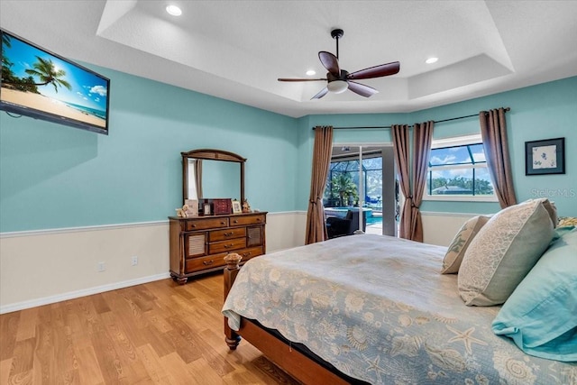 bedroom with access to exterior, recessed lighting, a raised ceiling, wood finished floors, and baseboards