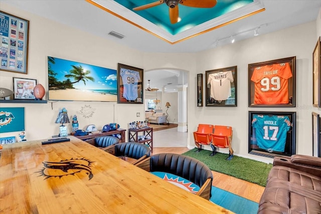 interior space featuring a tray ceiling, arched walkways, visible vents, ceiling fan, and wood finished floors