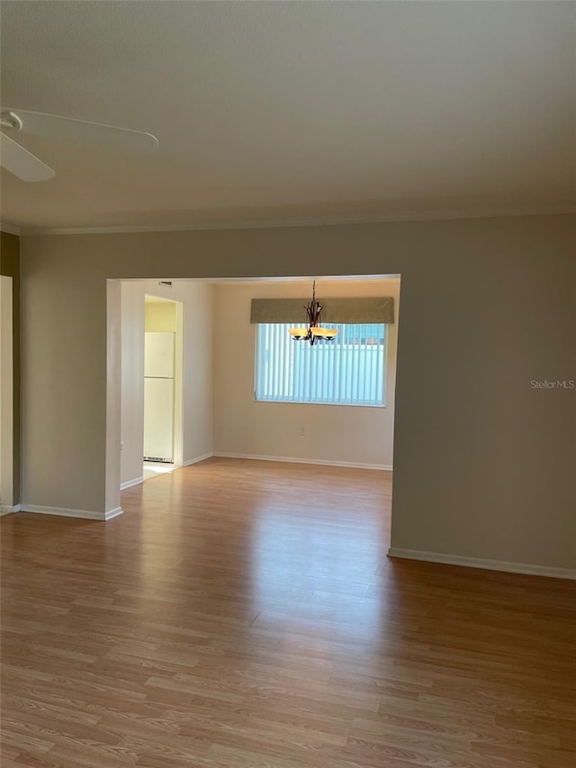 empty room featuring ornamental molding, a chandelier, and light hardwood / wood-style flooring