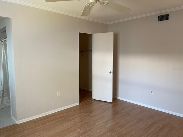 unfurnished bedroom with wood-type flooring, ornamental molding, and a closet