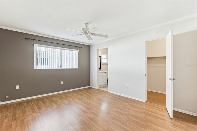 unfurnished bedroom with crown molding, light hardwood / wood-style floors, a closet, and a spacious closet