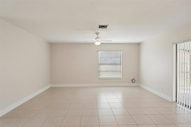 empty room with ceiling fan, light tile patterned floors, and a healthy amount of sunlight