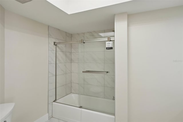 bathroom with toilet and bath / shower combo with glass door